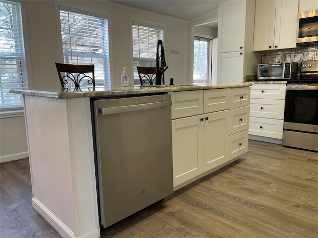 120 County Road 1719, Clifton, TX 76634 - kitchen with stainless steel appliances, light wood finished floors, plenty of natural light, white cabinetry, and crown molding