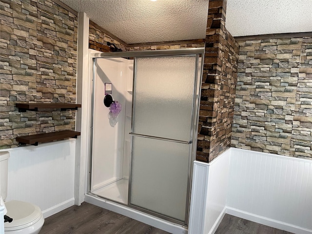 120 County Road 1719, Clifton, TX 76634 - bathroom featuring wood finished floors, a stall shower, toilet, a textured ceiling, and a wainscoted wall