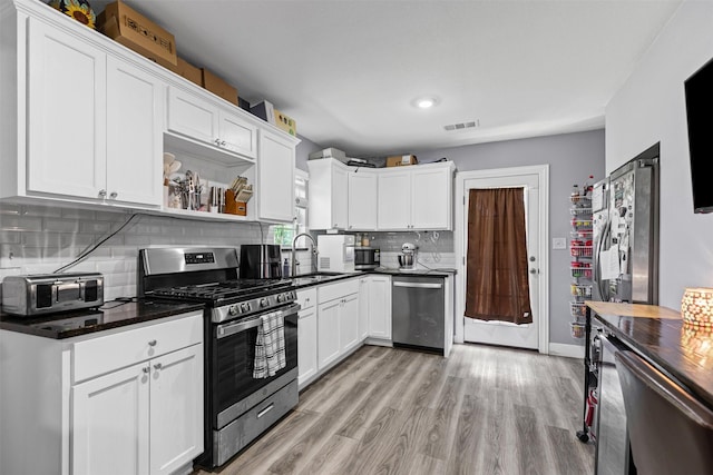 105 S Lavaca St, Whitney, TX 76692 - kitchen with stainless steel appliances, a sink, tasteful backsplash, and white cabinetry