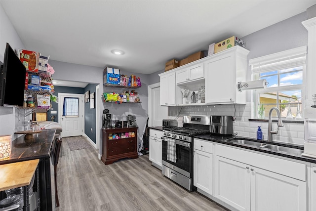 105 S Lavaca St, Whitney, TX 76692 - kitchen with stainless steel gas range, open shelves, a sink, tasteful backsplash, and white cabinets