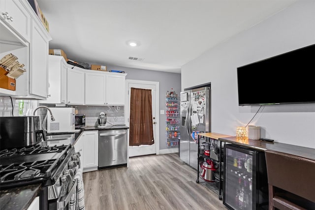105 S Lavaca St, Whitney, TX 76692 - kitchen featuring appliances with stainless steel finishes, beverage cooler, dark countertops, white cabinetry, and recessed lighting