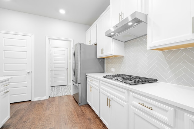 1519 Fairweather Way, Forney, TX 75126 - kitchen with under cabinet range hood, stainless steel appliances, tasteful backsplash, white cabinetry, and wood finished floors