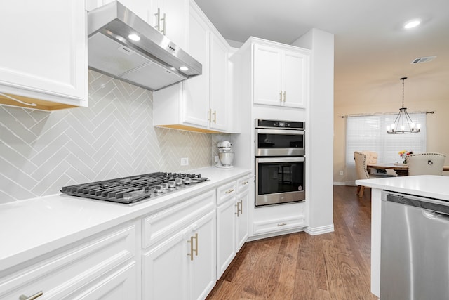 1519 Fairweather Way, Forney, TX 75126 - kitchen featuring appliances with stainless steel finishes, ventilation hood, wood finished floors, a chandelier, and tasteful backsplash