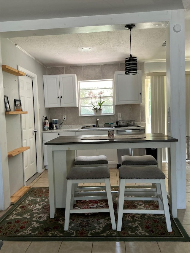 1403 Little St, Copperas Cove, TX 76522 - kitchen with a textured ceiling, white cabinetry, a sink, a breakfast bar, and ornamental molding