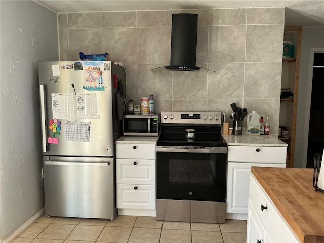1403 Little St, Copperas Cove, TX 76522 - kitchen featuring stainless steel appliances, wall chimney exhaust hood, butcher block countertops, light tile patterned floors, and white cabinets