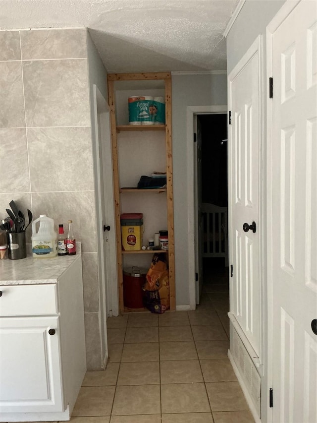 1403 Little St, Copperas Cove, TX 76522 - corridor with light tile patterned floors, a textured ceiling, and tile walls