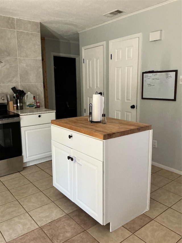 1403 Little St, Copperas Cove, TX 76522 - kitchen with electric stove, wood counters, light tile patterned floors, white cabinets, and ornamental molding