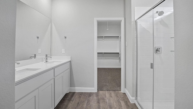 105 Leon Ave, Rhome, TX 76078 - full bathroom featuring wood finished floors, a shower stall, a spacious closet, double vanity, and a textured wall