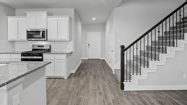 105 Leon Ave, Rhome, TX 76078 - kitchen with stainless steel appliances, light wood-style flooring, light stone countertops, baseboards, and white cabinetry