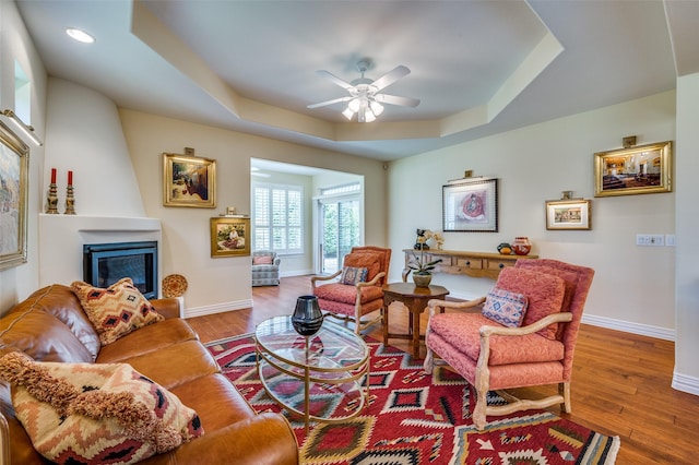 382 Burnswick Isles Way, Frisco, TX 75036 - living room featuring baseboards, a raised ceiling, a large fireplace, wood finished floors, and a ceiling fan