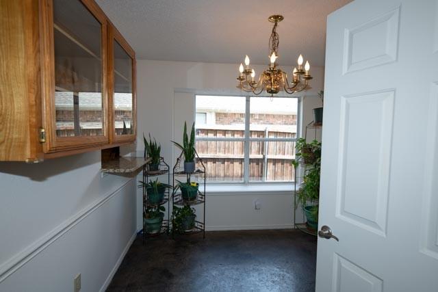 1111 Bayshore St, Allen, TX 75002 - unfurnished dining area with a chandelier, baseboards, and dark colored carpet