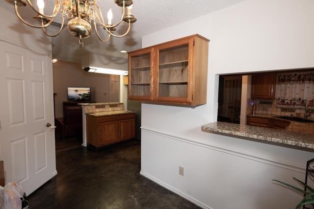1111 Bayshore St, Allen, TX 75002 - kitchen with a chandelier, glass insert cabinets, and brown cabinetry