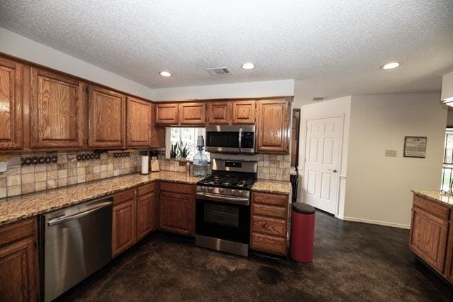 1111 Bayshore St, Allen, TX 75002 - kitchen featuring appliances with stainless steel finishes, tasteful backsplash, brown cabinetry, recessed lighting, and plenty of natural light