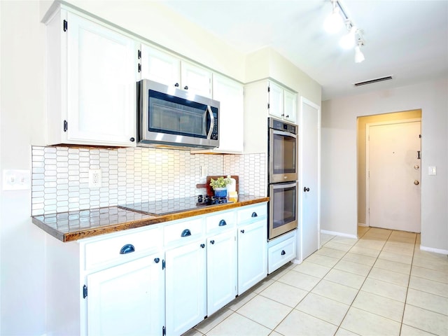 3609 Marwick Dr, Plano, TX 75075 - kitchen featuring appliances with stainless steel finishes, white cabinets, rail lighting, tasteful backsplash, and light tile patterned floors