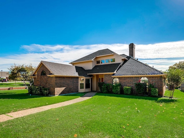 1101 Shawnee Trl, Carrollton, TX 75007 - traditional home with a shingled roof, brick siding, a front lawn, and a chimney