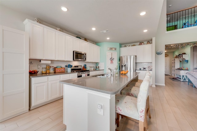 14024 Callisto Way, Haslet, TX 76052 - kitchen featuring appliances with stainless steel finishes, a sink, a center island with sink, white cabinetry, and a breakfast bar area