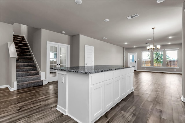106 Camelia St, Garland, TX 75043 - kitchen with dark wood-style flooring, french doors, dark stone countertops, a kitchen island, and white cabinetry