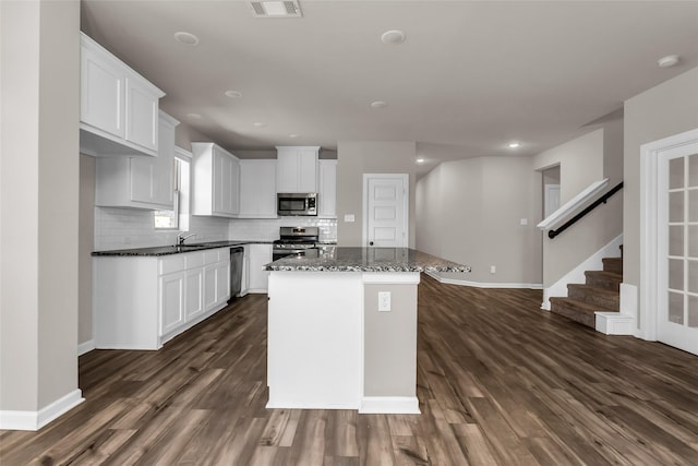 106 Camelia St, Garland, TX 75043 - kitchen with appliances with stainless steel finishes, a sink, dark wood-style flooring, tasteful backsplash, and white cabinets