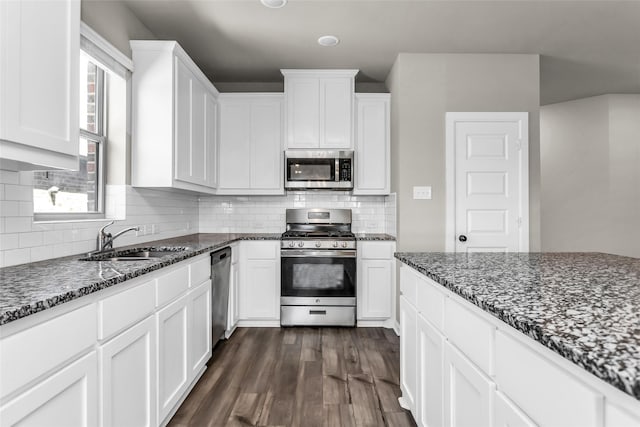 106 Camelia St, Garland, TX 75043 - kitchen with stainless steel appliances, a sink, dark wood-style flooring, dark stone counters, and white cabinets
