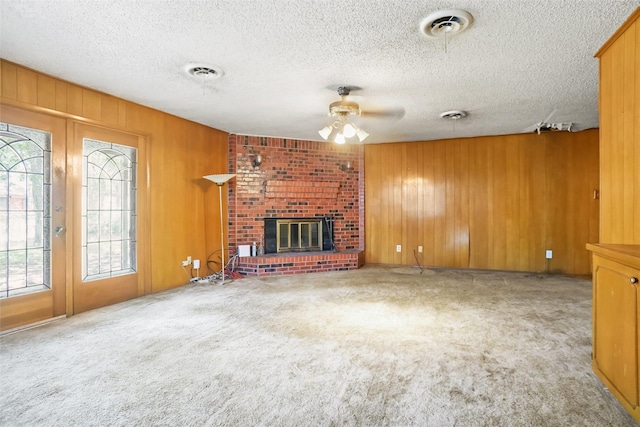 520 Circleview Dr S, Hurst, TX 76054 - unfurnished living room featuring ceiling fan, wooden walls, a fireplace, carpet floors, and a textured ceiling