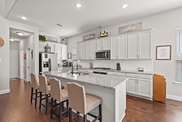 3620 Brahman Ct, Mckinney, TX 75071 - kitchen with a sink, stainless steel microwave, refrigerator with ice dispenser, white cabinetry, and a center island with sink