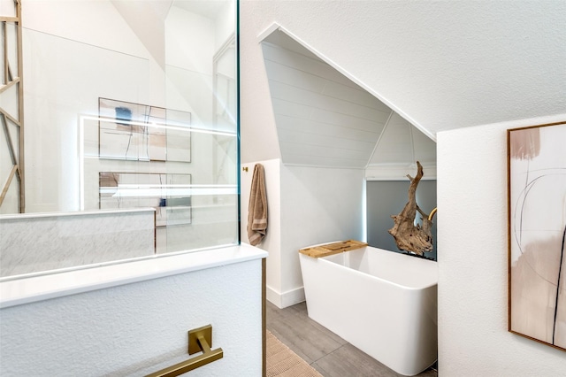 1495 Bent Trail Cir, Southlake, TX 76092 - bathroom with a freestanding tub, vaulted ceiling, wood finished floors, and baseboards