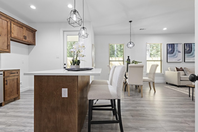 14815 Goliad Dr, Log Cabin, TX 75148 - kitchen with a breakfast bar area, recessed lighting, light countertops, brown cabinetry, and light wood finished floors
