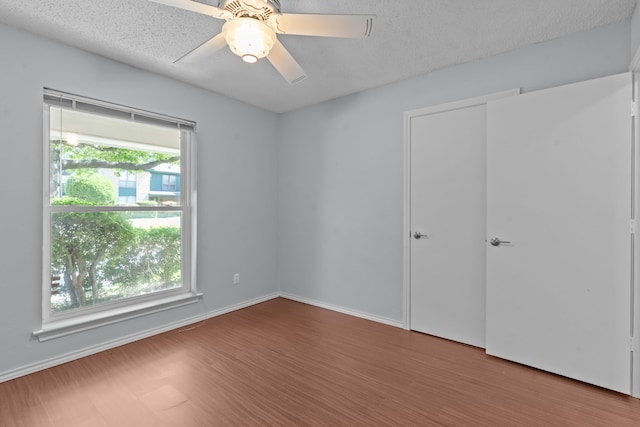 7725 Westwind Dr, Fort Worth, TX 76179 - unfurnished bedroom featuring wood finished floors, baseboards, ceiling fan, and a textured ceiling