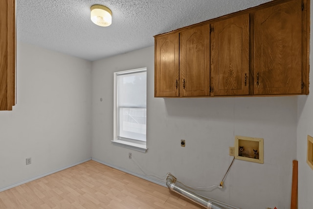 7725 Westwind Dr, Fort Worth, TX 76179 - laundry room featuring hookup for a washing machine, cabinet space, a textured ceiling, hookup for an electric dryer, and light wood-style floors