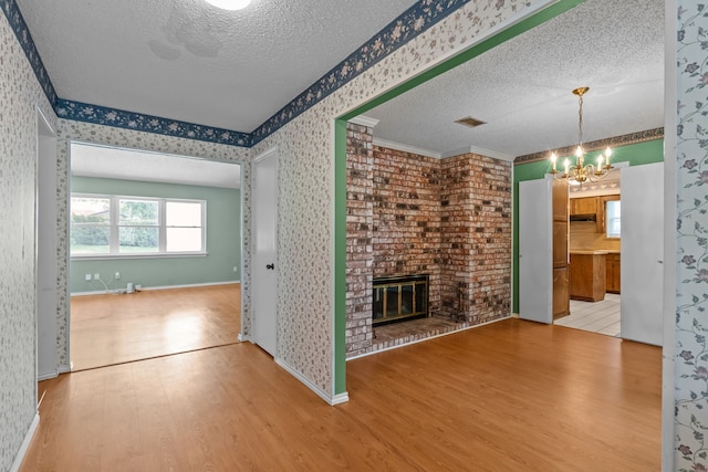 7725 Westwind Dr, Fort Worth, TX 76179 - unfurnished living room with a textured ceiling, wood finished floors, a chandelier, wallpapered walls, and a fireplace