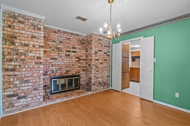 7725 Westwind Dr, Fort Worth, TX 76179 - unfurnished living room featuring a textured ceiling, a chandelier, a brick fireplace, wood finished floors, and crown molding
