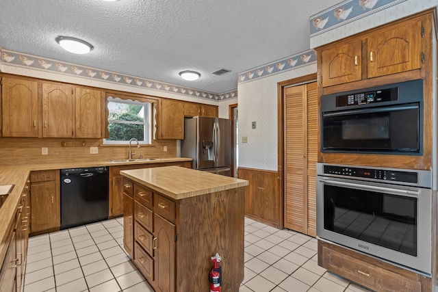 7725 Westwind Dr, Fort Worth, TX 76179 - kitchen featuring appliances with stainless steel finishes, a sink, a textured ceiling, a wainscoted wall, and light tile patterned floors