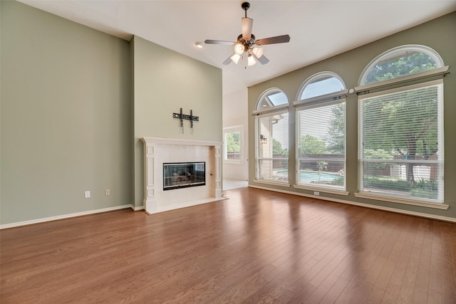 3208 Greenglen Dr, Carrollton, TX 75007 - unfurnished living room with wood finished floors, ceiling fan, a premium fireplace, a high ceiling, and baseboards