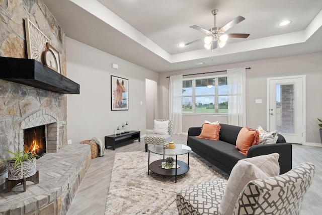 123 Cedar Elm Ln, Nevada, TX 75173 - living area featuring light wood-style flooring, a raised ceiling, ceiling fan, a stone fireplace, and baseboards