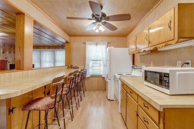 1245 Hodgson St, Fort Worth, TX 76115 - kitchen with white appliances, wood counters, light wood finished floors, ceiling fan, and a breakfast bar area