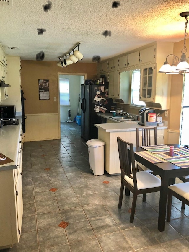 3107 Green Valley Ln, Arlington, TX 76014 - kitchen with a chandelier, wainscoting, freestanding refrigerator, a peninsula, and dark tile patterned floors