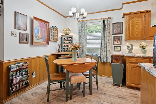 10930 Ridgemeadow Dr, Dallas, TX 75218 - dining room featuring crown molding, a chandelier, light wood finished floors, and a wainscoted wall