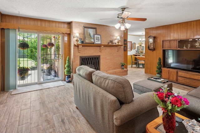 10930 Ridgemeadow Dr, Dallas, TX 75218 - living area featuring a ceiling fan, wood walls, wood finished floors, a textured ceiling, and a fireplace