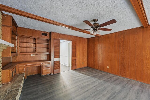 6330 Autumn Woods Trl, Dallas, TX 75232 - unfurnished living room with ceiling fan, wooden walls, dark wood-style floors, beam ceiling, and a textured ceiling