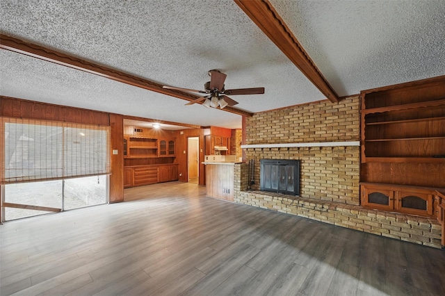6330 Autumn Woods Trl, Dallas, TX 75232 - unfurnished living room featuring beam ceiling, ceiling fan, a textured ceiling, wooden walls, and light wood finished floors