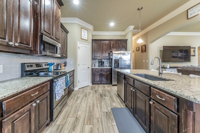 313 Donna Cir, Granbury, TX 76049 - kitchen with appliances with stainless steel finishes, a sink, dark brown cabinets, hanging light fixtures, and backsplash