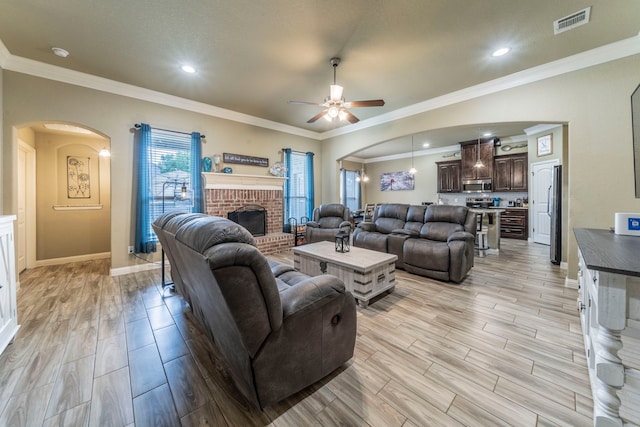 313 Donna Cir, Granbury, TX 76049 - living area featuring arched walkways, a ceiling fan, a fireplace, light wood-style flooring, and crown molding