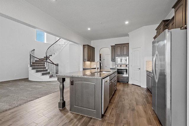 15232 Primrose Garden Ct, Aledo, TX 76008 - kitchen featuring appliances with stainless steel finishes, a sink, an island with sink, dark wood-type flooring, and dark brown cabinetry