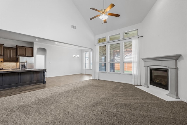 15232 Primrose Garden Ct, Aledo, TX 76008 - unfurnished living room featuring a glass covered fireplace, a chandelier, arched walkways, a ceiling fan, and high vaulted ceiling