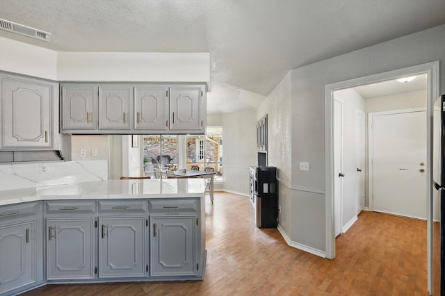 2500 Indian Hills Dr, Plano, TX 75075 - kitchen with gray cabinets, wood finished floors, and a peninsula