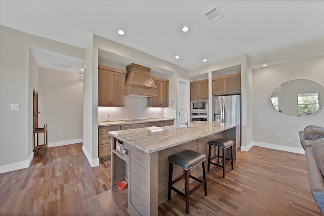 119 Cody Ave, Decatur, TX 76234 - kitchen featuring custom range hood, stainless steel appliances, a sink, a breakfast bar, and dark wood-style flooring