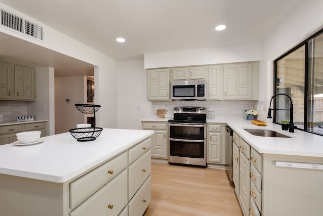 4218 Aralia St, Mesquite, TX 75150 - kitchen featuring appliances with stainless steel finishes, a sink, backsplash, light countertops, and light wood-style flooring