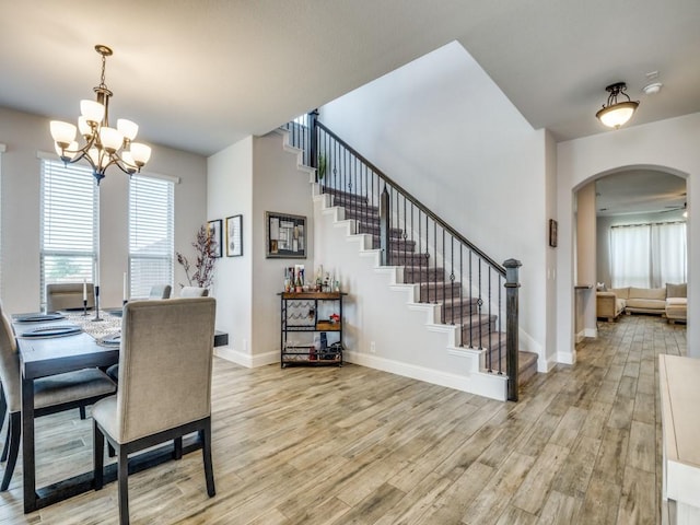 1241 Ronald St, Desoto, TX 75115 - dining space featuring arched walkways, light wood-style flooring, a chandelier, baseboards, and stairway