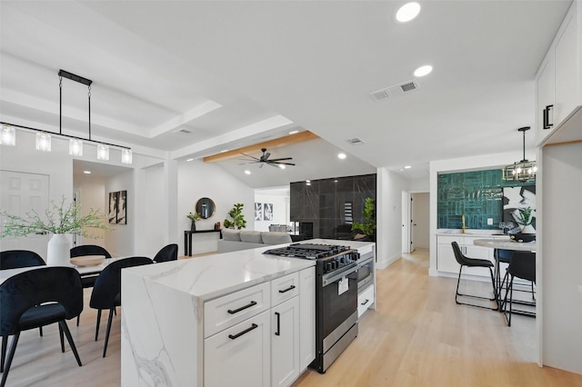 1429 Waterford Pl, Garland, TX 75044 - kitchen with stainless steel gas range oven, recessed lighting, white cabinets, light stone counters, and decorative light fixtures