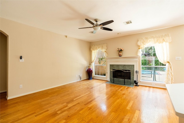 2017 Rumson Dr, Arlington, TX 76006 - unfurnished living room featuring arched walkways, light wood-type flooring, a ceiling fan, a fireplace, and baseboards